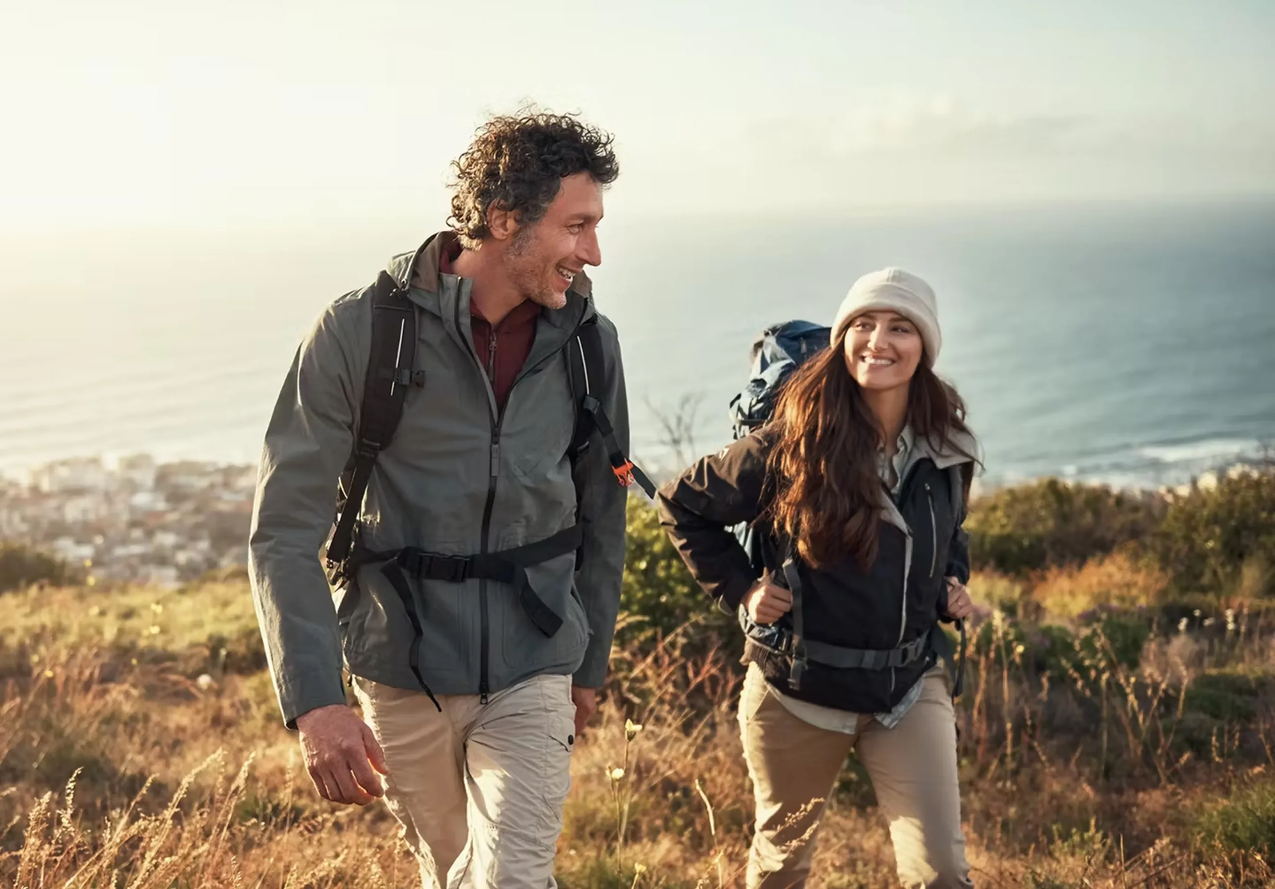 A man and a woman smile as they hike.